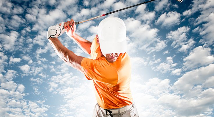 A golfer in an orange shirt swinging a club.